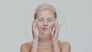 Studio portrait of young, beautiful and natural blond woman applying skin care cream. Face lifting, cosmetics and make