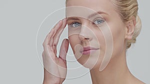 Studio portrait of young, beautiful and natural blond woman applying skin care cream. Face lifting, cosmetics and make