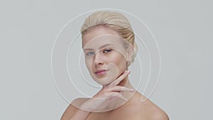Studio portrait of young, beautiful and natural blond woman applying skin care cream. Face lifting, cosmetics and make