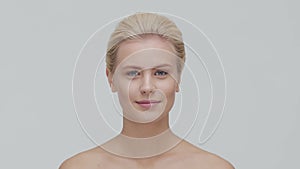 Studio portrait of young, beautiful and natural blond woman applying skin care cream. Face lifting, cosmetics and make