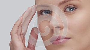 Studio portrait of young, beautiful and natural blond woman applying skin care cream. Face lifting, cosmetics and make