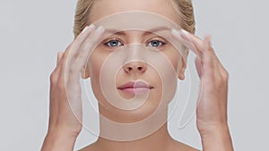 Studio portrait of young, beautiful and natural blond woman applying skin care cream. Face lifting, cosmetics and make