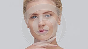 Studio portrait of young, beautiful and natural blond woman applying skin care cream. Face lifting, cosmetics and make