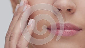 Studio portrait of young, beautiful and natural blond woman applying skin care cream. Face lifting, cosmetics and make