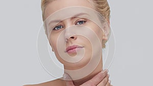 Studio portrait of young, beautiful and natural blond woman applying skin care cream. Face lifting, cosmetics and make