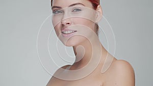 Studio portrait of young, beautiful and natural redhead woman applying skin care cream. Face lifting, cosmetics and make