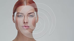 Studio portrait of young, beautiful and natural redhead woman applying skin care cream. Face lifting, cosmetics and make