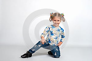 Studio portrait of young blonde smiling girl squatting on against white background