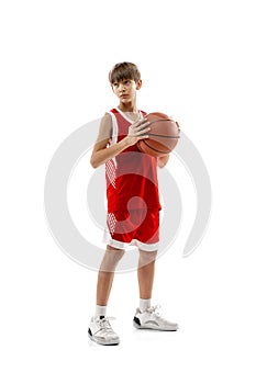 Studio portrait of young boy, basketball player in red uniform posing isolated over white background