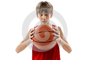 Studio portrait of young boy, basketball player in red uniform posing isolated over white background