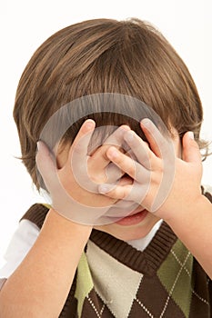 Studio Portrait Of Young Boy Covering Eyes