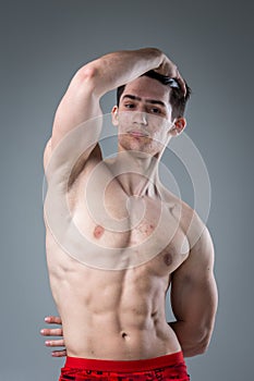 Studio portrait of a young brunette caucasian man on gray background posing. Puberty theme, problem skin, teen acne