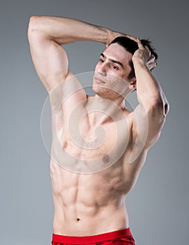 Studio portrait of a young brunette caucasian man on gray background posing. Puberty theme, problem skin, teen acne