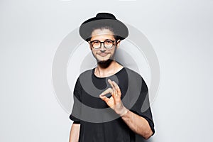 Studio portrait of young confident man, showing `ok` gesture on grey background.