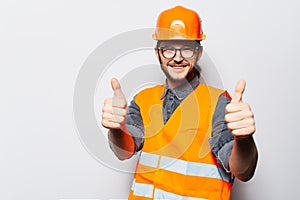 Studio portrait of young construction worker on white, showing thumbs up