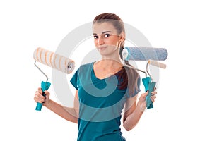 Studio portrait of young cutie brunette girl in uniform makes renavation with paint roller in hands posing on camera