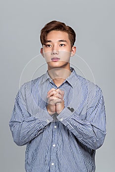 Studio portrait of a young East Asian man praying