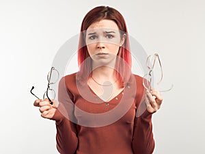 Studio portrait of a young girl with glasses in her hands with a frustrated and confused expression.