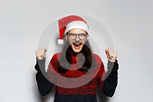 Studio portrait of young handsome happiness man with long hair, celebrate his triumph, doing winning gesture with both hands,