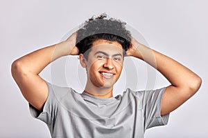 Studio portrait of young handsome smiling guy holding his head with his hands. Swarthy man with black curly hair