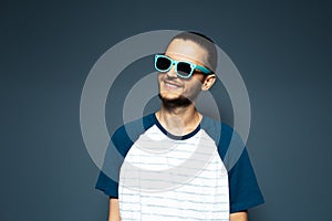 Studio portrait of young handsome smiling man, wearing sunglasses.