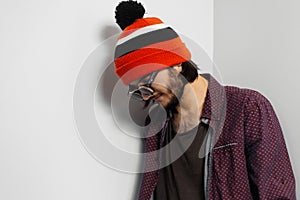 Studio portrait of young hipster guy, wearing round  sunglasses and orange hat on white background.