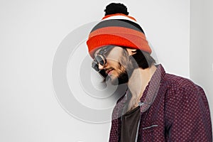 Studio portrait of young hipster guy, wearing round  sunglasses and orange hat on white background.