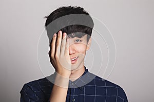 Studio portrait of a young man covering his face with one hand