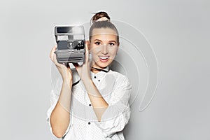 Studio portrait of young smiling girl, photographer making photo with vintage camera.