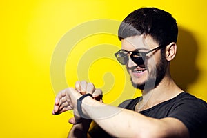 Studio portrait of young smiling man wearing black on yellow background.