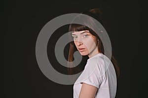 Studio portrait of a young woman against plain black background