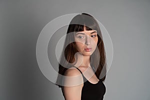 Studio portrait of a young woman against plain grey background