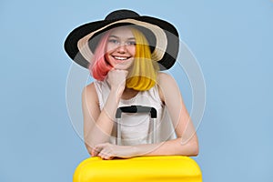 Studio portrait of young woman in summer hat with suitcase.