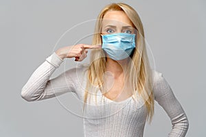 Studio portrait of young woman wearing a face protective mask isolated on gray background - flu virus epidemic