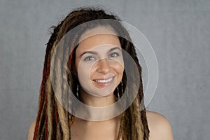 studio prtrait of young stylish beautiful smiling caucasian girl with dreadlocks hairstyle. Fashion and beauty concept