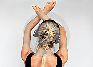 Studio rear view image of relaxing beautiful blonde young woman dancing during listening to music in headphones. Pretty female in