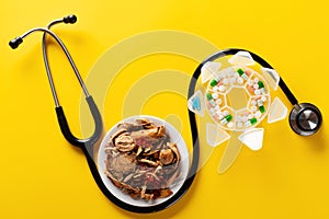 Studio shoot Chinese herb medicine and pills wrapped with a stethoscope on yellow