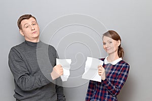 Studio shot of adult couple holding parts of torn white paper sheet