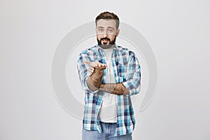 Studio shot of attractive caucasian bearded man pointing straight with palm and expressing willingness to receive answer