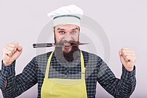 Studio shot of a bearded man holding a sharp knife with his teeth