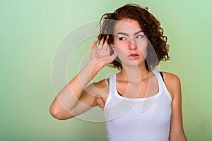 Studio shot of beautiful teenage girl thinking while listening a