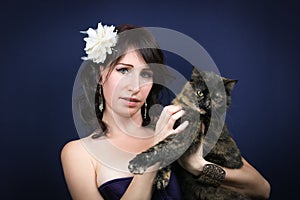 Studio shot of beautiful woman with her calico cat in the hand