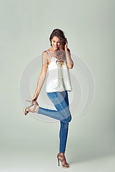 Everyday is a new opportunity to look awesome. Studio shot of a beautiful young woman getting undressed against a gray