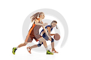 Studio shot of beginner basketball players, young girls, teen training with basketball ball isolated on white background