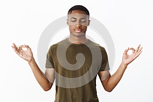 Studio shot of calm and peaceful young african american sportsman standing in lotus pose searching nirvana and patience