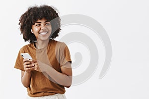 Studio shot of carefree friendly and creative stylish african american teenage girl in brown t-shirt turning right with