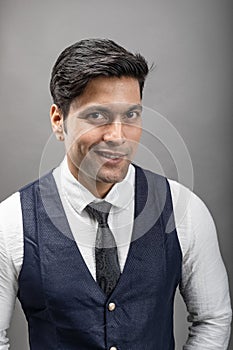 Studio shot of cheerful, young, handsome Indian business man in formal wear against grey background. Corporate male model. Fashion