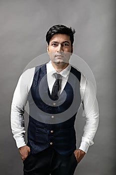 Studio shot of cheerful, young, handsome Indian business man in formal wear against grey background. Male model. Fashion Portrait