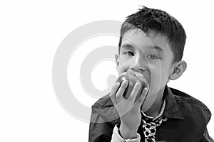 Studio shot of cute boy eating apple