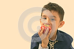 Studio shot of cute boy eating apple